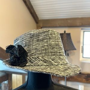 Black and white tweed like fedora style hat with black flower on the side